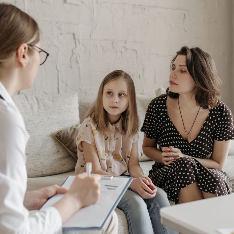 A clinician taking notes with a young patient and a parent
